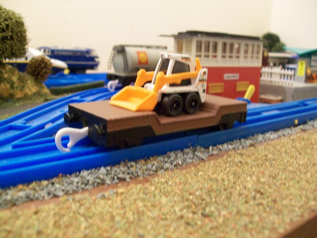 Re-painted Plarail Lowmac wagon, with a Matchbox, skid steer shovel load. 
The Lowmac is a standard Tomy Thomas model, which came in green livery (th